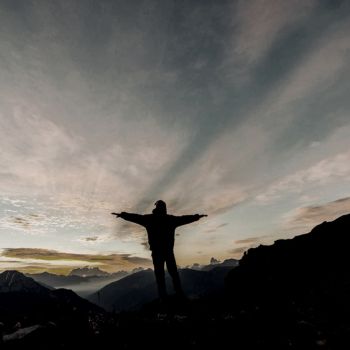 a person standing on the top of a mountain during sunrise